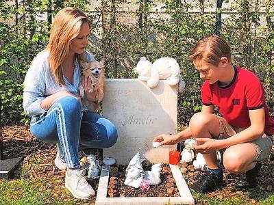 Pieter brandt een kaarsje bij Amelies graf. Moeder Petra en Floke, het hondje dat ze van haar zus kreeg na Amelies overlijden, kijken toe.  © Ilse Pauwels