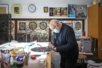 Joost Caen aan het werk in zijn atelier, een schatkamer die heel wat waardevolle glasramen onderdak biedt. © Ans Brys