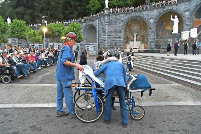 De mijnwerkers-brancardiers helpen een zieke vrouw tijdens de kaarsjesprocessie in Lourdes. © Hans Put