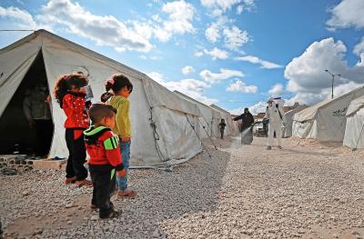 In een vluchtelingenkamp in Syrië kijken kinderen toe hoe hun omgeving wordt ontsmet voor het coronavirus. © Belga Image