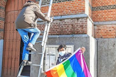 Medewerkers hangen een regenboogvlag aan de parochiekerk in Wiekevorst als teken dat die holebi’s omarmt. © Gerry Bellekens